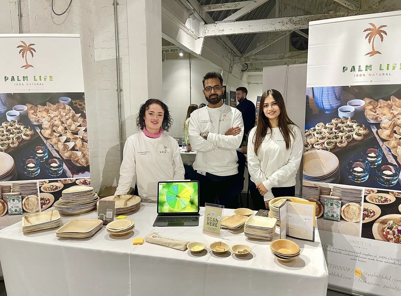 Three people presenting palm leaf tableware at a Palm Life event stand
